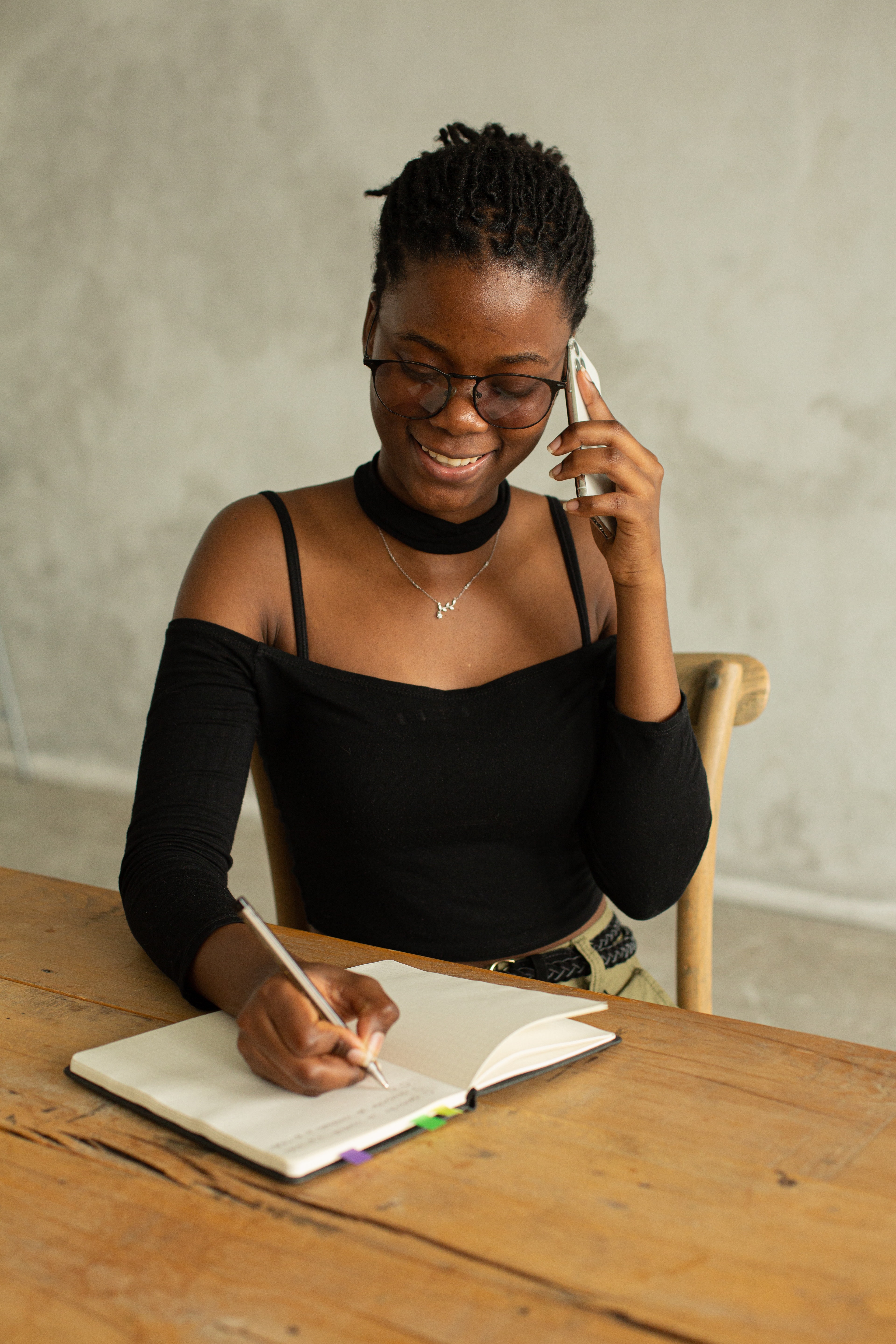 Lady on her phone, calling someone and writing down notes.